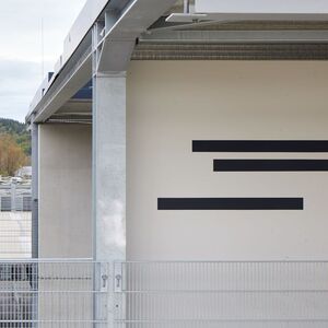 Schwarze horizontale Streifen an der Außenwand eines Gebäudes auf einem Parkdeck.