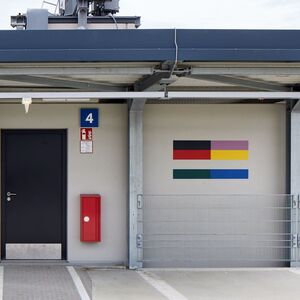 Das Foto zeigt ein Kunstwerk aus farbigen horizontalen Steifen an der Wand eines Gebäudes.