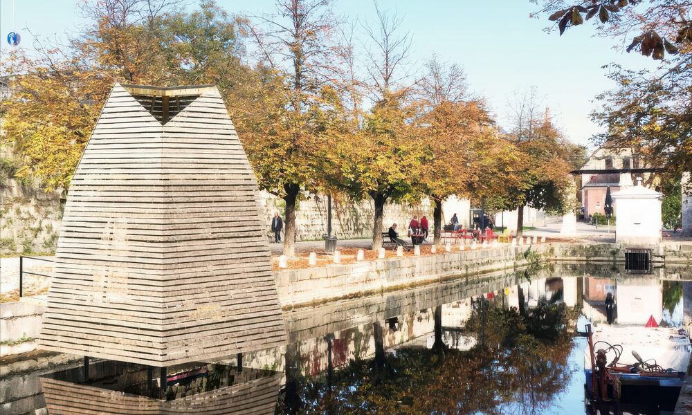 Im Lendhafen steht im Wasser eine quadratischer Turm aus Holzlatten