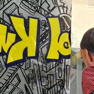 Glasfläche wird mit einer Folie mit gelbem Schriftzug beklebt.