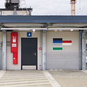 Das Foto zeigt ein Kunstwerk aus farbigen horizontalen Steifen an der Wand eines Gebäudes.