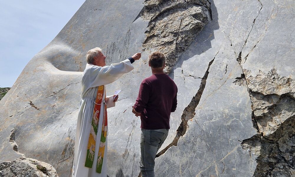 Ein Priester segnet einen großen Stein, der zum Kunstwerk bearbeitet wurde