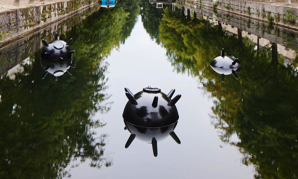 Drei kugelförmige Objekte mit Stacheln schwimmen in einem Kanal im Wasser.