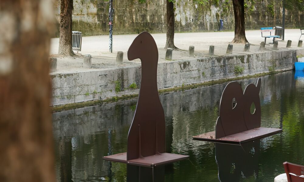 Braune Skulptur aus dünnen Holzplatten, die im Lendhafen schwimmt, mit der Form eines Lindwurms