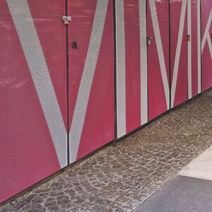 Hofdurchgang mit pinker Streckmetallfassade und schwarz-weißen Streifen am Boden