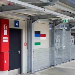 Das Foto zeigt ein Kunstwerk aus farbigen horizontalen Steifen an der Wand eines Gebäudes.