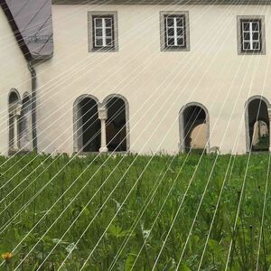 Weisse Fäden überspannen einen mit Gras bepflanzten Innenhof