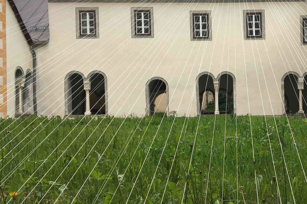 Weisse Fäden überspannen einen mit Gras bepflanzten Innenhof