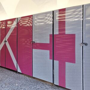 Hofdurchgang mit pinker Streckmetallfassade und einem weissen Schrifftzug MMKK.