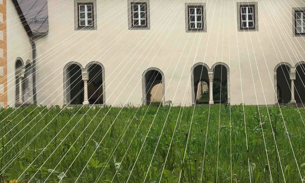 Weisse Fäden überspannen einen mit Gras bepflanzten Innenhof